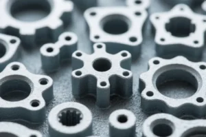 Close-up of precision metal parts with multiple holes and machined profiles, showing OEM component samples on a textured surface.