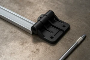 Custom injection-molded plastic hinge bracket mounted to an aluminum profile on a workshop surface.