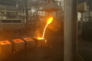 Molten metal pouring into ceramic shell molds during investment casting process in a foundry workshop.