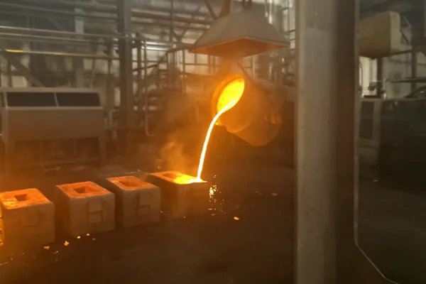 Molten metal pouring into ceramic shell molds during investment casting process in a foundry workshop.