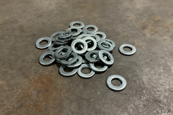 Pile of zinc-plated flat washers on a metal workshop table