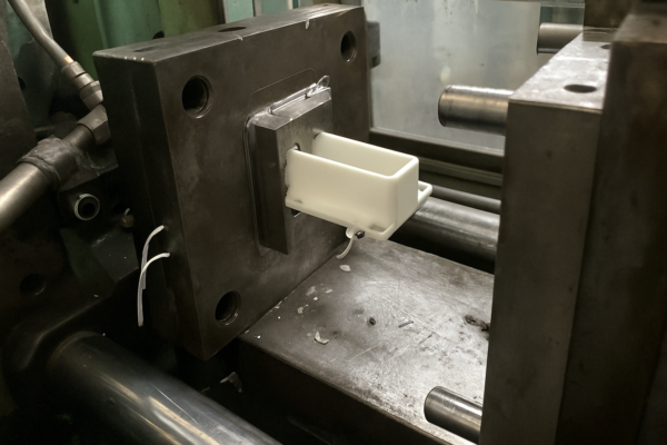 Injection molding machine producing a custom plastic part as the mold opens and the white component is ejected during production.