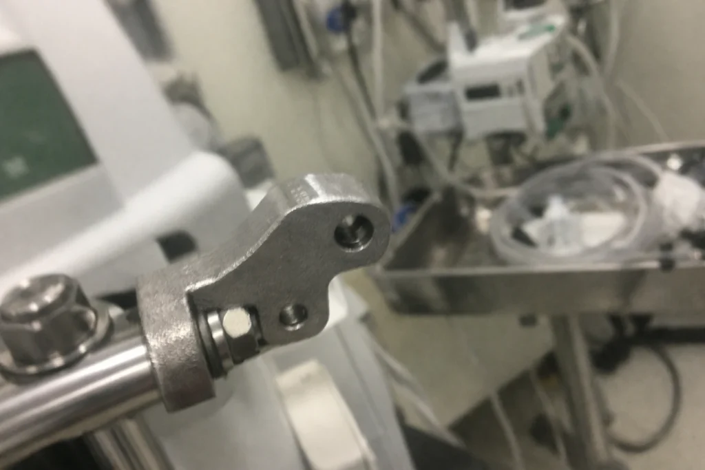 Custom cast metal bracket component mounted on a medical device frame in a clinical equipment setting